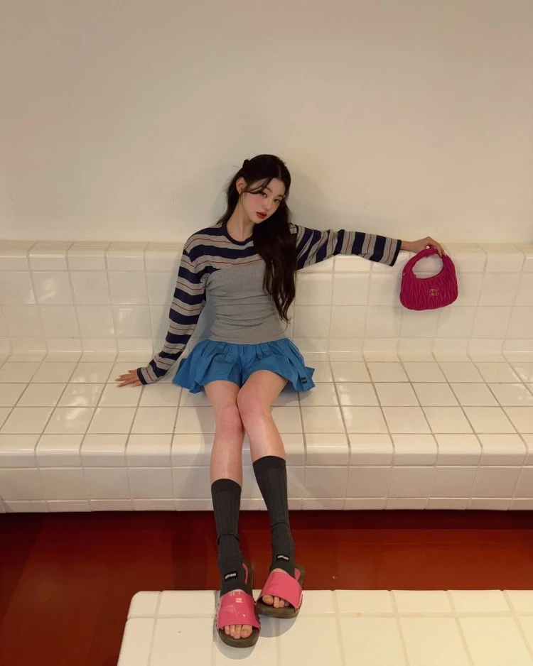 張員瑛融合甜美與街頭感的混搭範例,大學T選擇偏寬鬆的純棉材質,下身搭配中長版百褶裙,重點在於裙子的挺度與層次感。