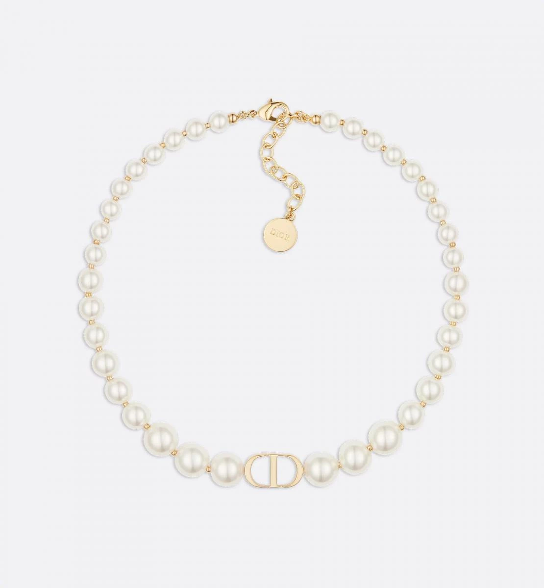 Dior 30 Montaigne 短項鍊以金色飾面金屬串連白色樹脂珍珠，小巧的 CD 標誌成為亮眼焦點。靈感來自品牌位於蒙田大道30號的巴黎總店，象徵經典與新意的交會。頸鍊式設計勾勒出俐落線條，散發一種既優雅又具現代感的女性力量，是專為懂得平衡柔軟與堅定的女人而生。