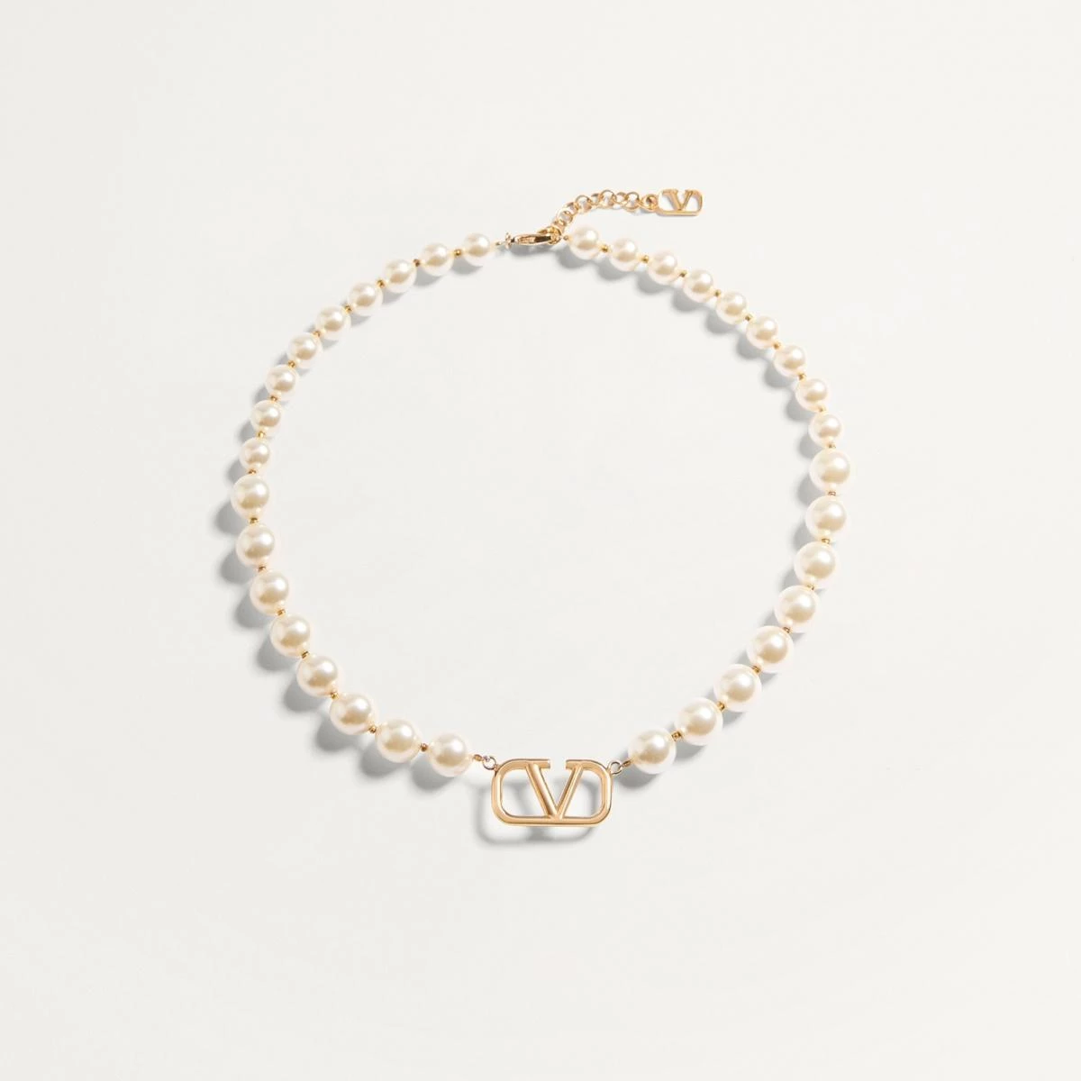 Valentino 的 VLogo Signature 項鍊以金色金屬搭配樹脂珍珠，中央的鏤空 V 字 Logo 簡約而醒目。它不像誇張的珠寶那樣搶戲，而是在不動聲色間散發精緻氣場。適合搭配白襯衫或羊毛針織，讓「簡約」成為最有力量的宣言，一如品牌一貫的羅馬優雅。