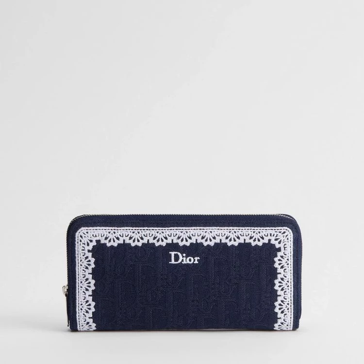 Dior Oblique Voyageur全新薄款長夾以深藍色Dior Oblique緹花為主體,搭配白色蕾絲邊框與刺繡標誌,拉鍊式設計讓內部收納一目了然,能平整放置鈔票與日常必需品。
