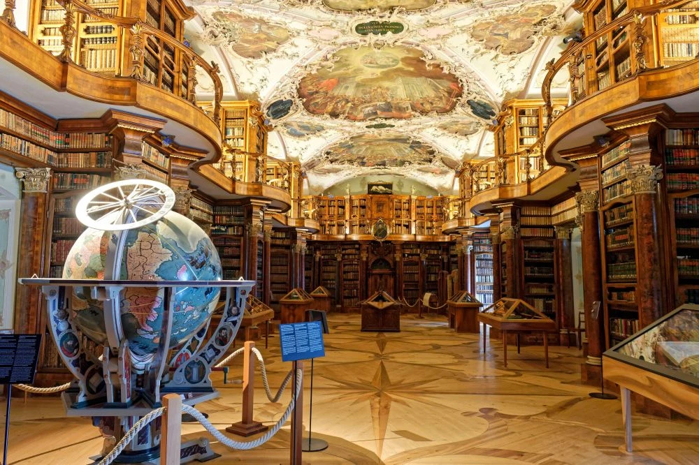 坐落於瑞士東部的聖加侖市,聖加侖修道院圖書館(Abbey Library of St. Gallen)被譽為歷史最悠久、最具價值的修道院圖書館之一,其歷史可追溯至 8 世紀中葉。當年,愛爾蘭修士 Gallus 在此地建立類似現今的小型讀書會,隨著修道院逐漸發展,圖書館也隨之建立。其最令人驚嘆的亮點,是圖書館內保存完好的木質內裝與巴洛克風格天頂壁畫,值得一去。