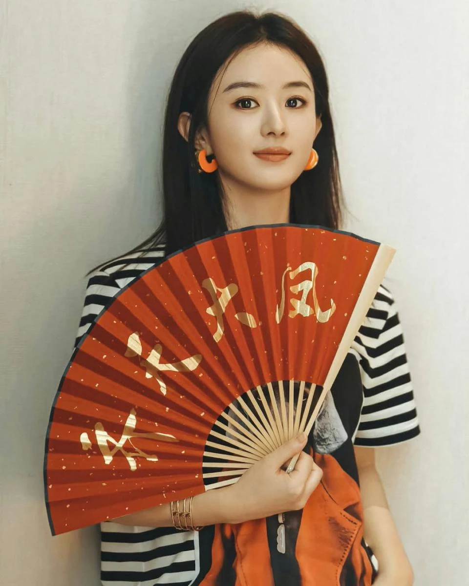 條紋向來是經典不敗的日常元素,但趙麗穎選擇的是線條清楚、間距俐落的黑白條紋,避免過於休閒或童趣。搭配亮橘色耳環,成功在臉部附近製造視覺焦點,讓整體精神度瞬間提升。這類配色對比清楚卻不花俏,非常適合輕熟女借鏡。條紋負責穩定造型基底,配件則負責「提亮」,是相當實用的減齡公式。