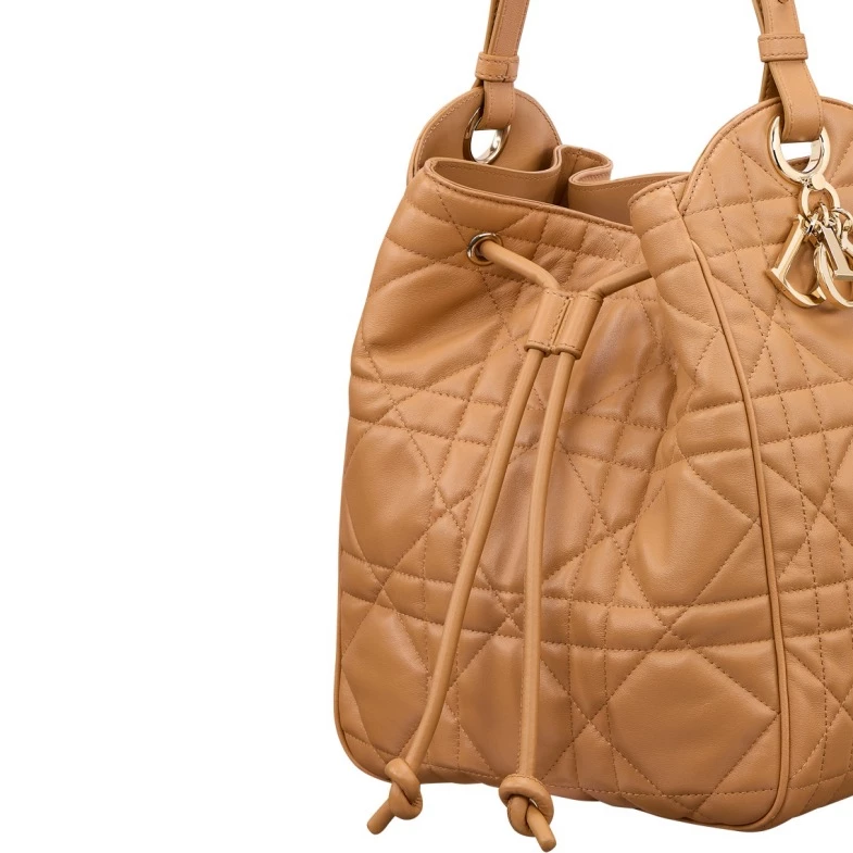Dior 藤格紋是一種經典且具高度辨識度的圖騰,其靈感源自 19 世紀拿破崙三世風格的藤編椅。這些椅子曾用於 Dior 創辦人 Christian Dior 在 1947 年首次高級訂製服發表會中,用來款待貴賓。藤格紋以對稱交錯的線條與菱形、橢圓圖案構成,融合了法式優雅與幾何美感。1995 年,Lady Dior 包款問世,首次將藤格紋壓印在小羊皮上,並因戴安娜王妃的愛用而聲名大噪,成為品牌最具代表性的作品之一,而「D-Motion」並運用其符碼,並將他放大呈現,正整體擁有更為簡潔、摩登的線條。
