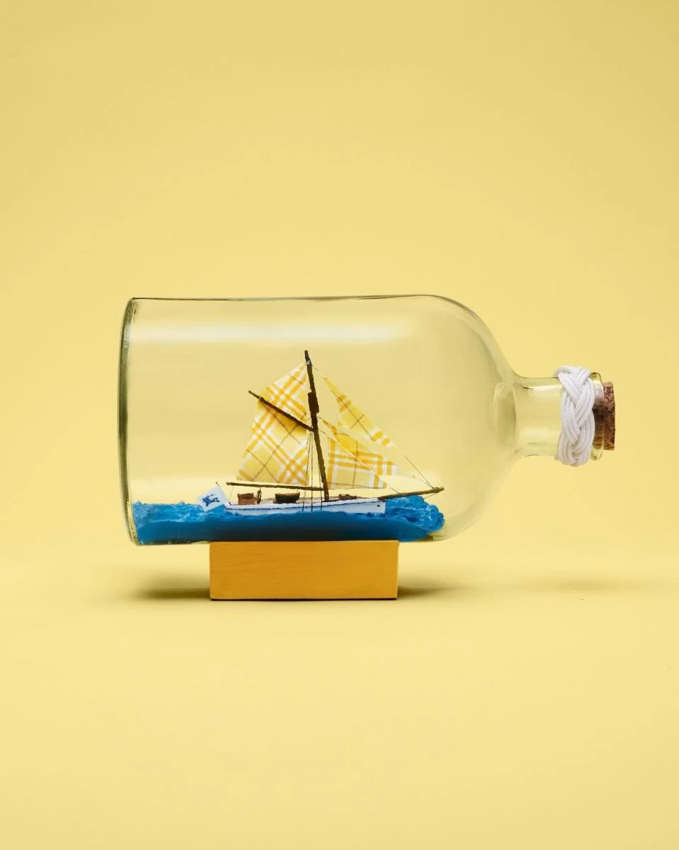 來自Burberry的社群照片,由歐洲瓶中船協會(European Association of Ships in Bottles)主席Alan Rogers所創作的迷你瓶中船藝術品,作品名稱為「Check Mate」,將一艘帶有黃色格紋船帆的房屋船精巧地呈現在透明玻璃瓶中。