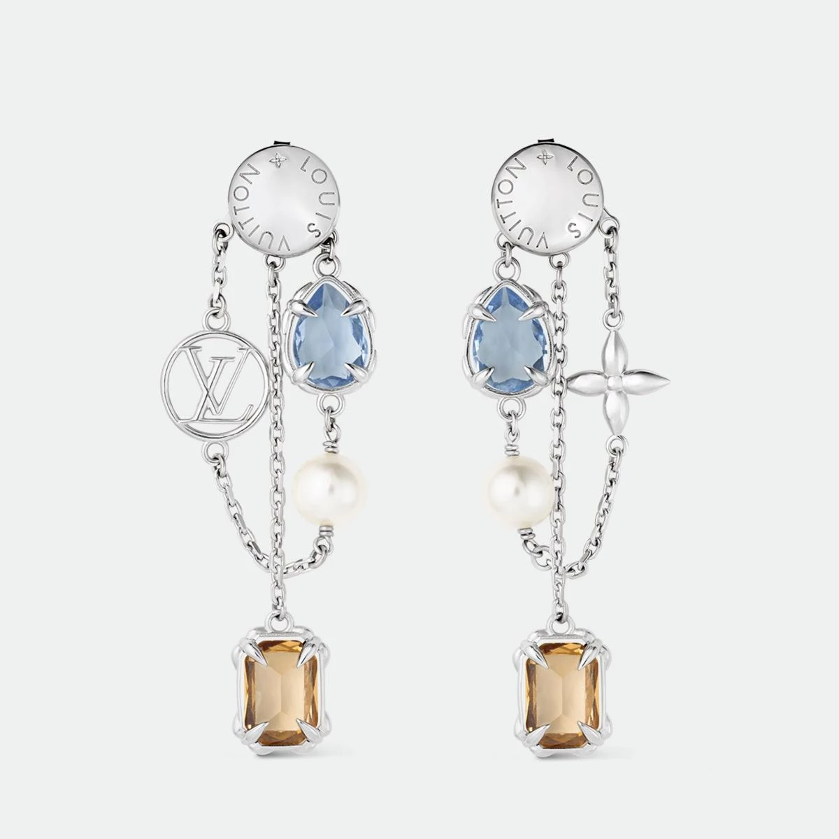 路易威登的 Heirloom Pendant 耳環是獻給魅力女性的最佳禮物。它以不對稱鍊帶串連彩色鋯石與樹脂珍珠,一側耳環飾以 LV Circle 標誌,另一側則綴以 Monogram 花卉圖案,搭配細膩的花卉造型爪鑲,展現出女性的多面與獨特。琥珀與水藍鋯石色調交錯,像晨光與夜幕的交替,柔美卻有力量。無論搭配白襯衫或絲質洋裝,皆能展現不費力的時髦。