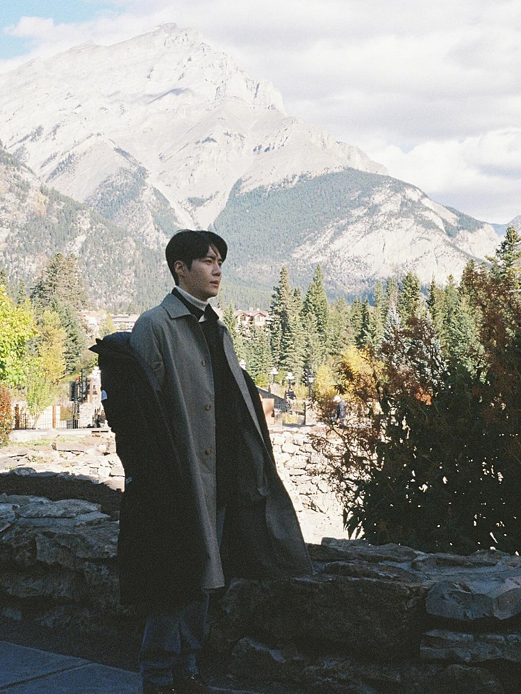 金宣虎面對冷颼颼的天氣,以「洋蔥式穿搭」應對!最外層上身黑色長版羽絨大衣,再搭上俐落剪裁的羊毛大衣,巧妙把戶外感與都會感,內搭高領針織延續一貫的低調配色,讓視覺重心自然集中在層次與材質變化上。這種「大衣+羽絨」的雙外套穿法,看似隨性,其實非常考驗比例與長度拿捏。