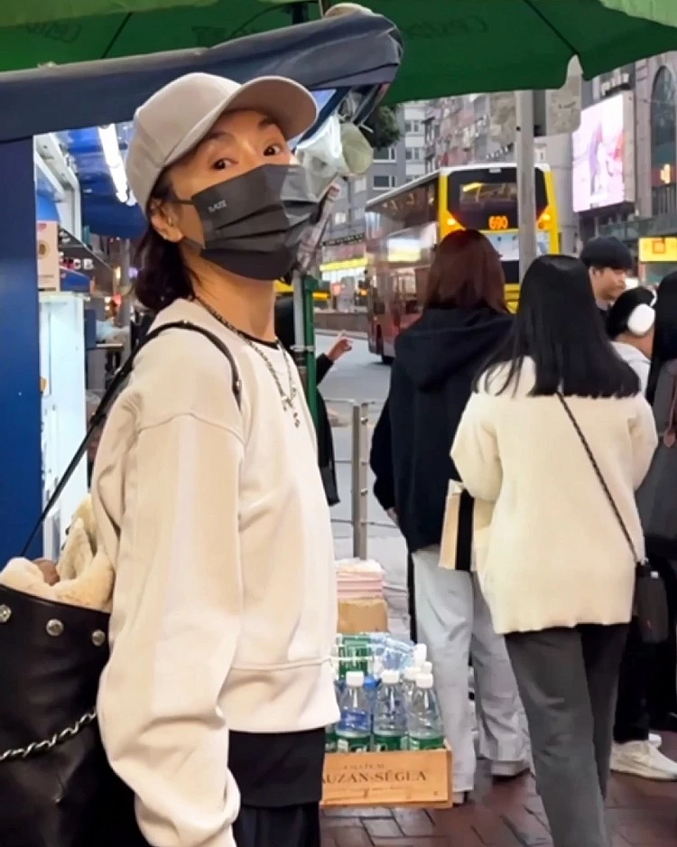 張曼玉在香港街頭遊走,以白色簡約圓領衛衣搭配Alo的黑色棉褲穿搭,頭頂上戴著白色棒球帽,營造出輕鬆自在的運動休閒感