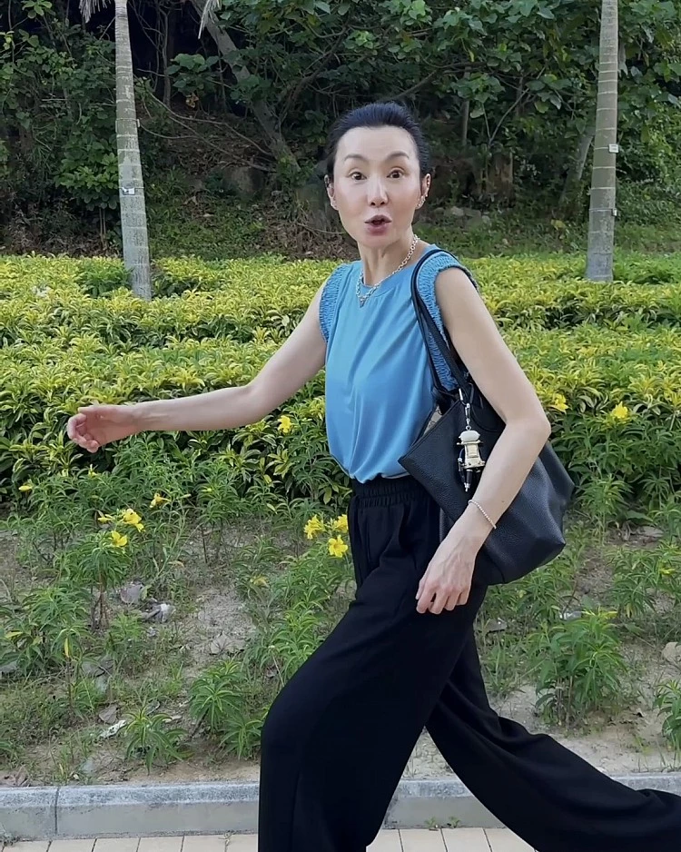 張曼玉換上不同Look,以一件水藍色無袖背心搭配黑色棉質寬褲,手上依舊拎著Gucci最新「Giglio」包款