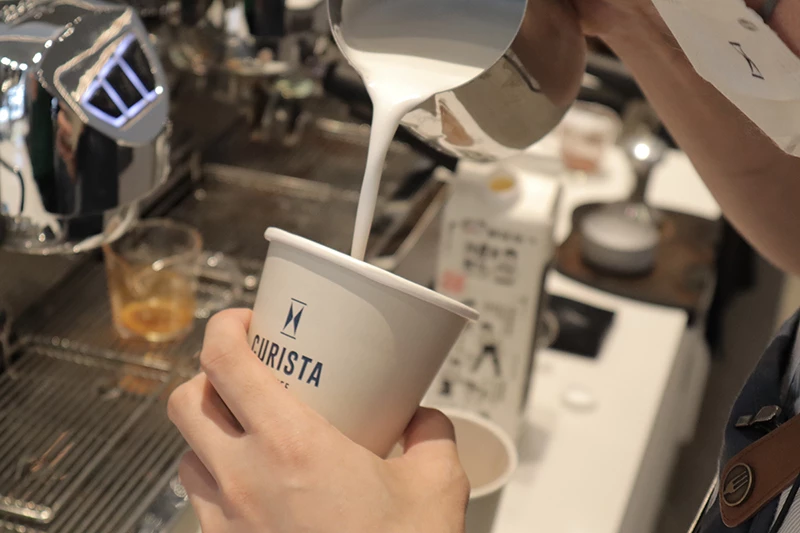 台北東區的CURISTA COFFEE 奎士咖啡,咖啡師正在沖泡拿鐵咖啡,最後加入台灣的小農鮮乳,口味香濃又滑順。