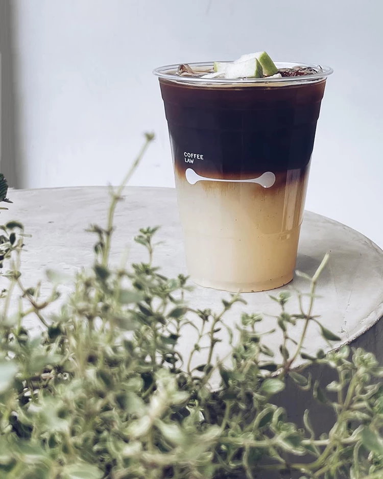 位在台北東區的Coffee Law新品青芭樂冰美式,白色與咖啡色的漸層,前方還有一堆小草當點綴。