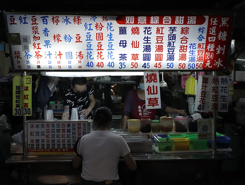 外國人迷戀台灣的夜市小吃,這家位在南機場的如意甜湯,正有一個穿著白色上衣的女生正在享用。