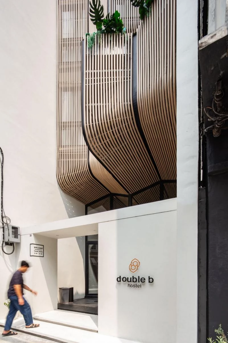 泰國 VMA Design Studio 的「Double B Hostel」,坐落於舊城狹長街廓中,設計團隊結合在地材料、傳統木作工藝與現代工法,創造出具流動感的木質立面,並結合開放中庭巧妙引入自然光與通風,打造融合在地文化與交流氛圍的獨特休憩空間。