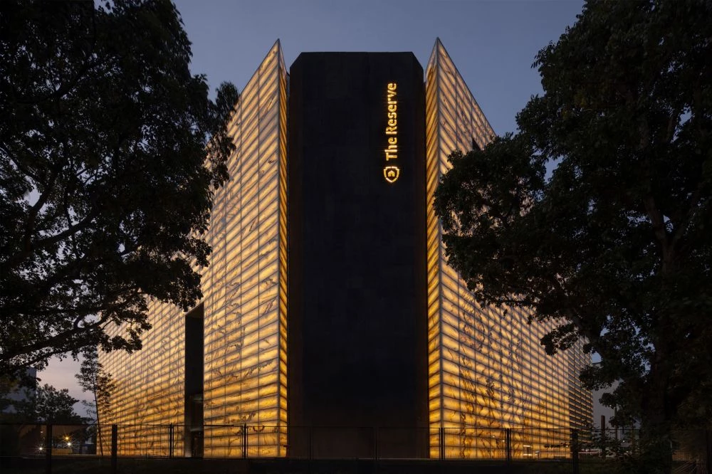 新加坡 MonoLab Studio 的「The Reserve」,將舊電子倉庫改造為貴重資產保管庫,以帶有瑪瑙紋理的夾層玻璃立面,象徵傳統與新興科技的交會,內部則在保留建築形態的同時,透過兩倍高的大門、特殊層架與空間動線等設計,營造戲劇性的氛圍,詮釋保管庫神秘的場域特質。