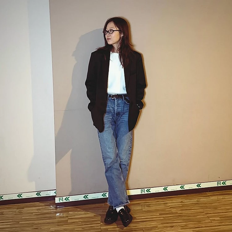 這套造型完美示範孔曉振最擅長的不費力成熟感。她以微寬版的俐落黑色西裝外套搭配白色上衣，建立乾淨、有精神的上半身輪廓，下身則選擇高腰直筒牛仔褲，刻意保留一點寬度，讓整體不會過於正式。