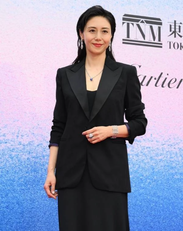 為了對抗歲月帶來的身形變化,松嶋菜菜子在私服中偏好運用硬挺剪裁來重塑精神面貌。正如此套穿搭所示,她完美平衡了「大膽用色」與「俐落廓形」,巧妙以一件高飽和的寶藍色拼接西裝,打破深色系的沉悶,藉此鮮豔色調瞬間提亮氣色,展現出不刻意裝嫩的飽滿活力。而在下半身的選擇上,她則利用高腰闊腿褲優化比例並延展視覺腿長,營造出隨性大氣的從容感。
