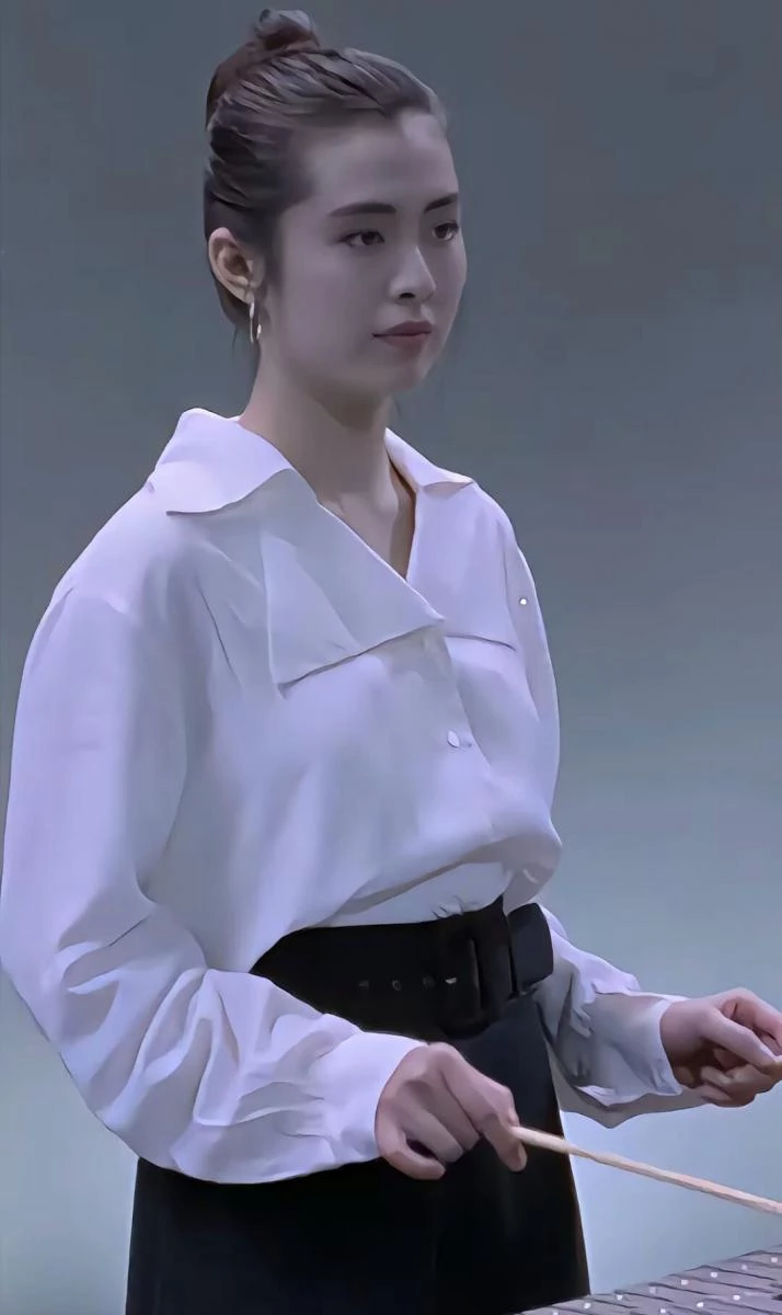 白襯衫與高腰黑裙，向來是歷久不衰的經典組合，而王祖賢的詮釋關鍵在於「結構感」。她選擇略為寬鬆的大翻領襯衫，刻意放大的領片為上半身建立清楚輪廓，也自然拉長頸部線條；下身則搭配腰線明確的高腰西裝裙，並以同色寬版腰帶強調比例，使整體身形看起來更加修長而穩定。襯衫紮入裙頭，卻保留布料的自然鬆度，讓正式單品不顯拘謹，反而多了一份從容與氣場。這種以剪裁取勝、以比例說話的穿法，即使是30多年後的今日，依然是極具說服力的都會穿搭範本。