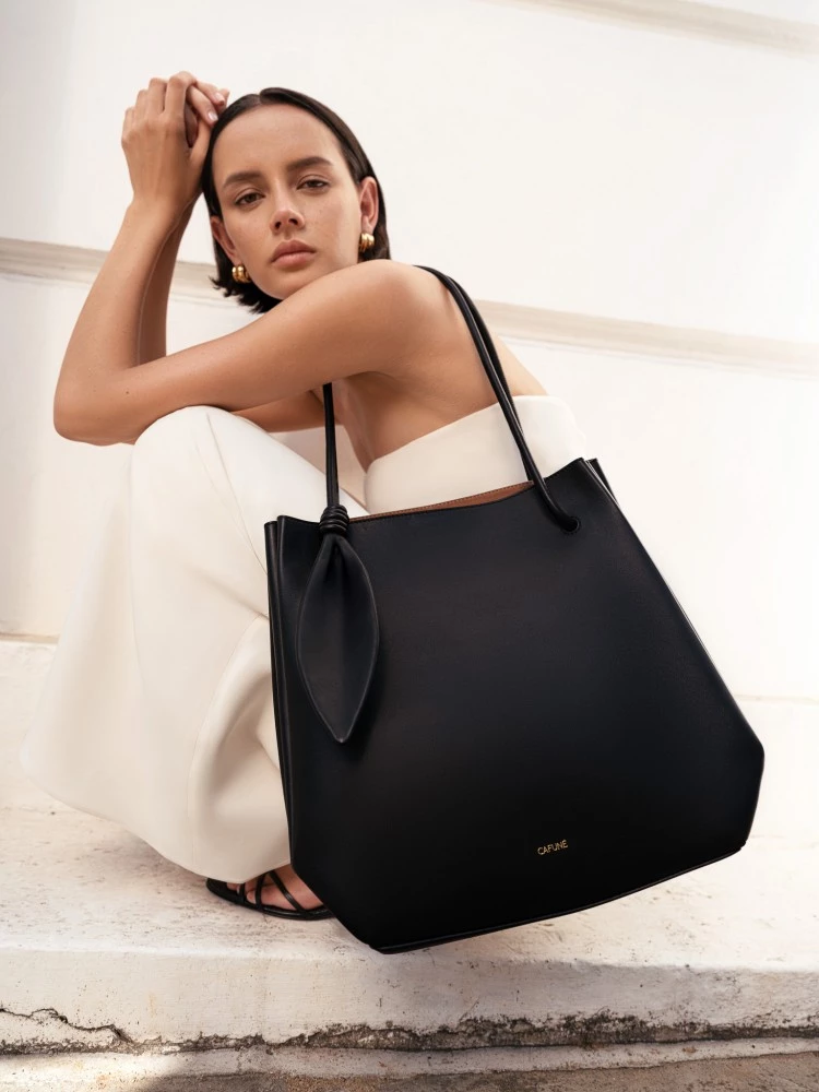 2025秋冬新作「Ori Tote」,靈感取自日本摺紙藝術,包身以幾何廓形描繪立體層次,兩側摺褶細節呼應折紙的俐落節奏,管狀手柄與葉形結飾增添自然韻律