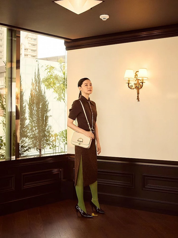 李英愛這套造型選擇Gucci深咖啡色套裝，沉穩優雅卻不失時尚張力，下身搭配亮眼的草綠絲襪打破沉悶，瞬間注入年輕活力。腳踩黑色尖頭高跟鞋，在配色上形成撞色對比，這套穿搭的減齡關鍵就在於：以沉穩底色為主，再透過鮮明配件或內搭增加活潑元素，有畫龍點睛的效果！