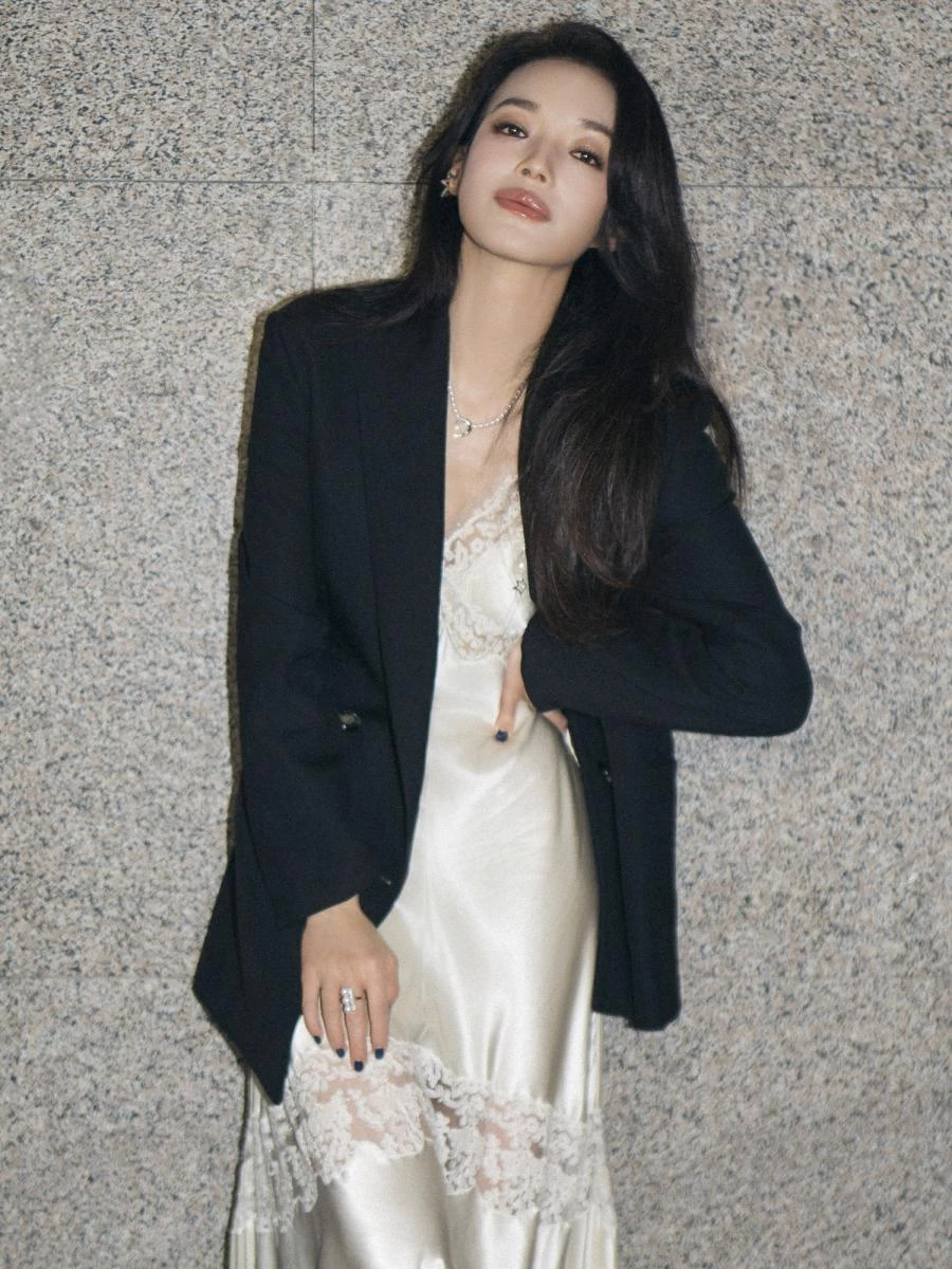 蕾絲與絲綢材質一向代表女性的柔美,但若單穿往往容易流於甜美或顯得成熟。舒淇選擇在淺米色蕾絲洋裝外搭剪裁俐落的黑色西裝外套,瞬間展現剛柔並濟的效果。這種 Mix & Match 的搭配不僅凸顯女性多層次魅力,也能修飾身形比例,讓浪漫與俐落氣息取得平衡,使整體造型更顯年輕有活力。她以此造型亮相影展,低調卻不失亮點,展現專屬她的自信與氣場。