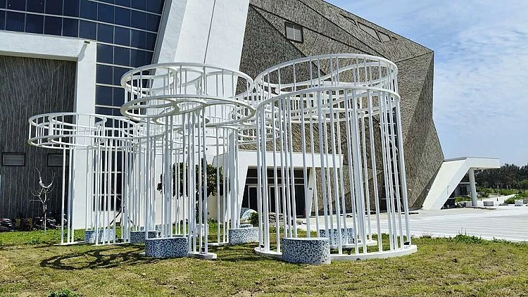 另一件，則是充滿寓意的《到海邊坐坐》，由好幾根鏤空圓柱組成，從下往上看，如同海面層層疊疊的波紋，一旁還有馬賽克拼貼的座椅，離開前，記得來這裡坐一坐吧。