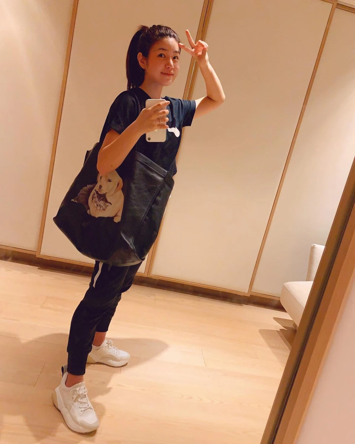 私下鏡子自拍這套是最生活化的一套,陳妍希穿著黑色貓咪印花T恤搭配黑色束口褲,手上還提著印有貓狗圖案的托特包,滿滿的愛貓愛狗人士既視感。全身黑色系加上白色厚底鞋做點綴,是最簡單好複製的顯瘦公式:上下身都是深色的情況下,鞋子選白色不僅不會讓造型顯得沉悶,厚底的份量感也能在寬鬆束口褲的襯托下,讓腳踝到小腿的線條更俐落。這套證明了餅乾鞋不只是拍照道具,日常私服穿搭一樣好駕馭。
