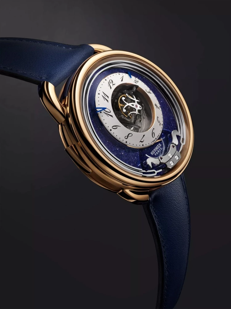 Hermès 愛馬仕 Arceau Duc Attelé 陀飛輪三問腕錶，將高級製錶工藝與馬術精神結合，呈現中央「三軸陀飛輪」與「三問報時」兩大複雜功能之美。錶盤上打造成駿馬形象的音錘；透過音錘擊打細長音叉形的淬火鋼音簧，進行時、刻、分報時，發出如教堂鐘聲般的樂音。