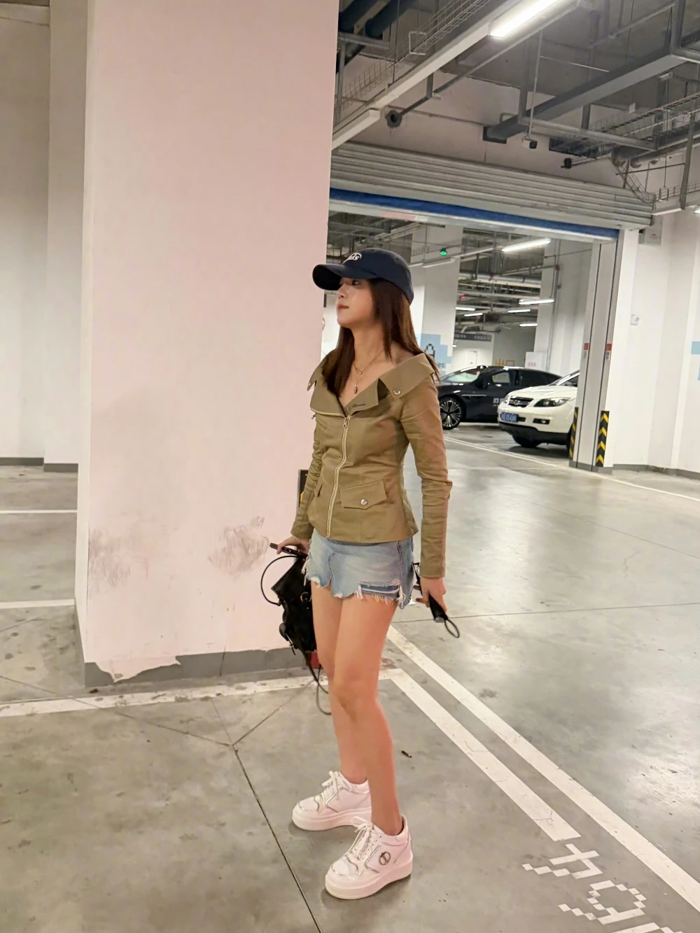 停車場隨拍這套,陳妍希選擇橄欖綠軍裝翻領外套搭配破壞感牛仔短褲,帽子與墨鏡加持整體率性感。腳上的白色厚底運動鞋則扮演「提亮」角色,深色系外套加上淺色丹寧短褲,本身對比已經很鮮明,白鞋再補上一筆亮色收尾,讓視線自然從上往下滑到腳踝處,達到修飾腿型的效果。這個公式很適合想穿深色軍裝、工裝外套,又擔心顯壯的人參考,重點就是鞋款一定要選淺色系厚底鞋來平衡上身的份量感。