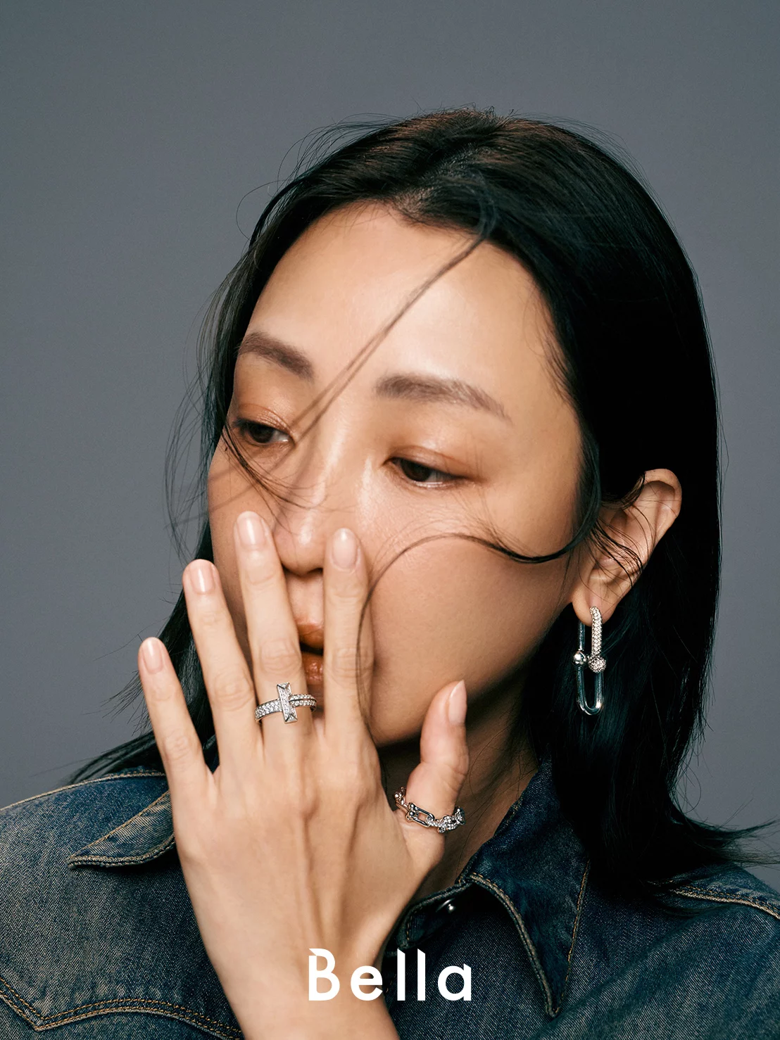  單寧襯衫,Fendi;(中指)「T1」系列 18K 白金鑲鑽戒指、(拇指)「HardWear」系列 18K 白金鑲鑽戒指及同系列耳環,all by Tiffany & Co.。