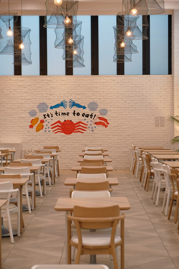 餐廳以函館港口城市為靈感,透過烏賊墨藝術牆、漁網燈飾與藍色系空間設計營造海洋氛圍。旅人可在此一邊享用早餐,一邊感受廚房熱氣與港灣氣息交織的節奏。