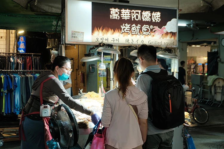 走進艋舺夜市,空氣裡總飄著一股熟悉的炭火香,那是「阿嬌姨烤魷魚」的味道。