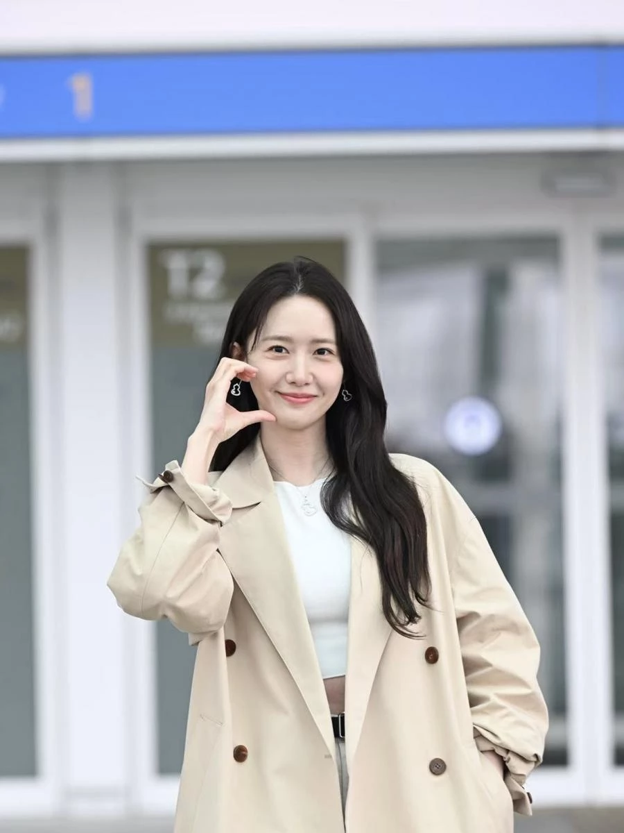 潤娥的機場穿搭選擇了經典米杏色風衣搭配白色短版上衣,乾淨、俐落、毫不費力。乍看是極簡的基本款組合,但真正的亮點落在耳畔及胸口的 Qeelin Wulu 18K白金鑽石及 Akoya 珍珠耳環及項鍊。珍珠的光澤如晨霧裡的第一滴露水,低調卻能瞬間點亮整體氣質。風衣偏中性的線條,透過珠寶柔和的曲線與光華,被轉化成更親切、更溫柔的氛圍。再加上 Wulu 象徵好運的寓意,使這套機場 Look 帶有「輕鬆出發、好事相隨」的明亮感。潤娥的穿搭非常高明,讓基本款風衣,也能靠一對質感珠寶,增添氣勢與完整度。