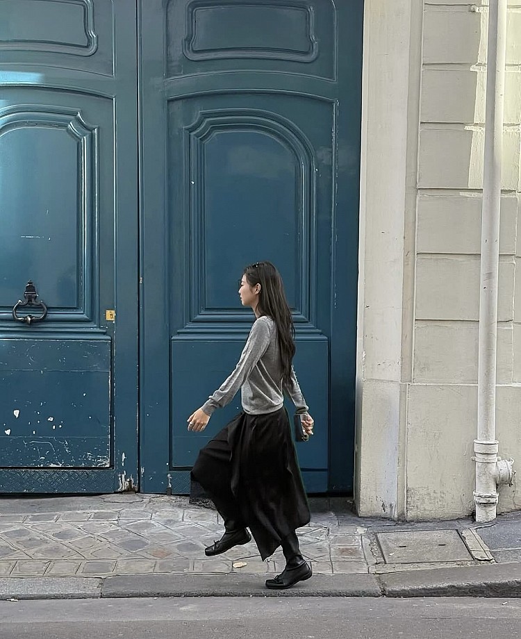 Jennie下身的黑色長裙隨步伐搖曳，搭配瑪莉珍長靴，增添份量感與街頭氣息。灰黑配色低調卻極具層次，最後以Chanel logo 毛帽點亮整體，帶出少女感與辨識度。