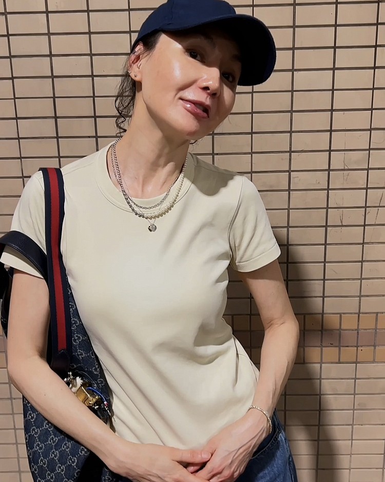 張曼玉這回選擇了深藍直筒牛仔褲，版型筆直、布料硬挺，讓身形比例瞬間被拉長。與第一套的淺藍寬褲相比，這件深藍丹寧更具沉穩感，卻因為版型不緊貼身材，完美展示「顯高＋減齡」兩大效果。她上身搭配奶茶色短袖T恤，簡單的中性色調襯托出牛仔褲的深藍質感，再加上一頂深藍棒球帽、 Gucci「Giglio」GG老花牛仔布托特包都呼應丹寧褲材質，讓整體造型更有一致性，也再次凸顯「牛仔單品」的百搭魅力。