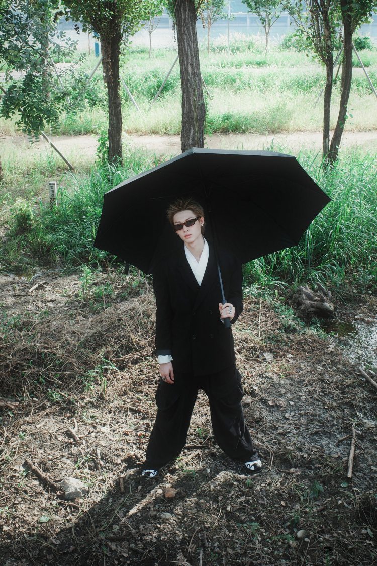 身高將近190公分的Cortis隊長Martin,本身就是「衣架子」,私服與舞台造型多半走極簡都會+未來感路線。寬肩飛行員外套、俐落短版上衣、低腰寬褲是他的招牌組合,善用黑、灰、銀等冷色系,讓整體看起來更有創作型偶像的前衛氣場。Martin的穿搭就像他的音樂一樣:結構感強、層次乾淨,把「少年感」轉化成新世代製作人風格。