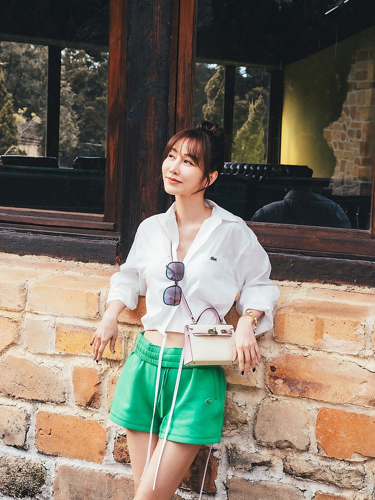 曾莞婷以俐落的Lacoste白襯衫短版造型搭配亮綠色短褲，打造出清新又率性的夏日Look。襯衫隨性挽起袖口、微露腰的小心機搭配，加上以Hermès Kelly 粉紅色、奶油白拼色迷你包作為吸睛配件，休閒之中增添高級感！