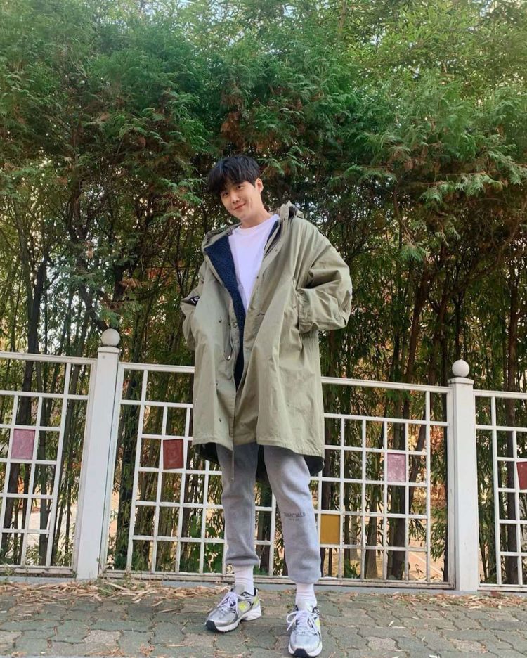 最後這一套，金宣虎以軍綠色連帽大衣作為主角，寬鬆剪裁加上偏長版型，讓整體看起來隨性卻不邋遢；內搭簡單白T，刻意保留穿搭的呼吸感，也讓外套本身的顏色與輪廓成為視覺重心。這種帶點機能感的外套，大家可能會擔心流於戶外風，但他透過配色與比例，把實穿感轉化成日常風格。