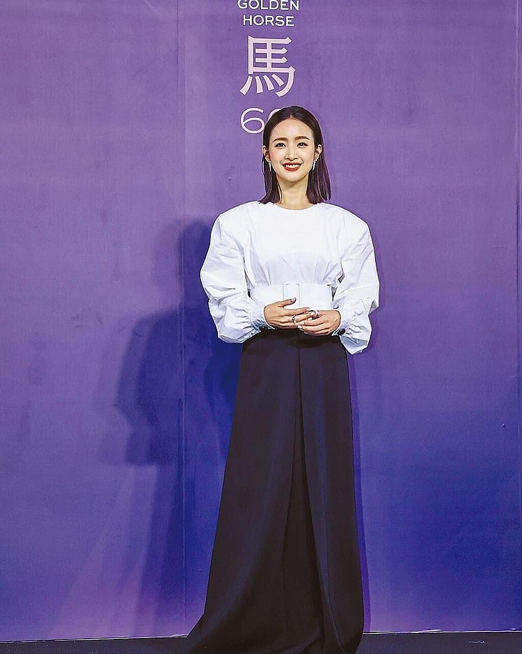 林依晨曾經在金馬60的活動上，選擇落肩剪裁的白色襯衫，蓬袖設計悄悄拉高肩線比例，下身搭配黑色拖地長裙，布料垂墜延伸出修長比例，以寬版白色腰帶束出清晰腰線，簡簡單單卻顯得高級的黑白造型，視覺上更顯年輕俐落！