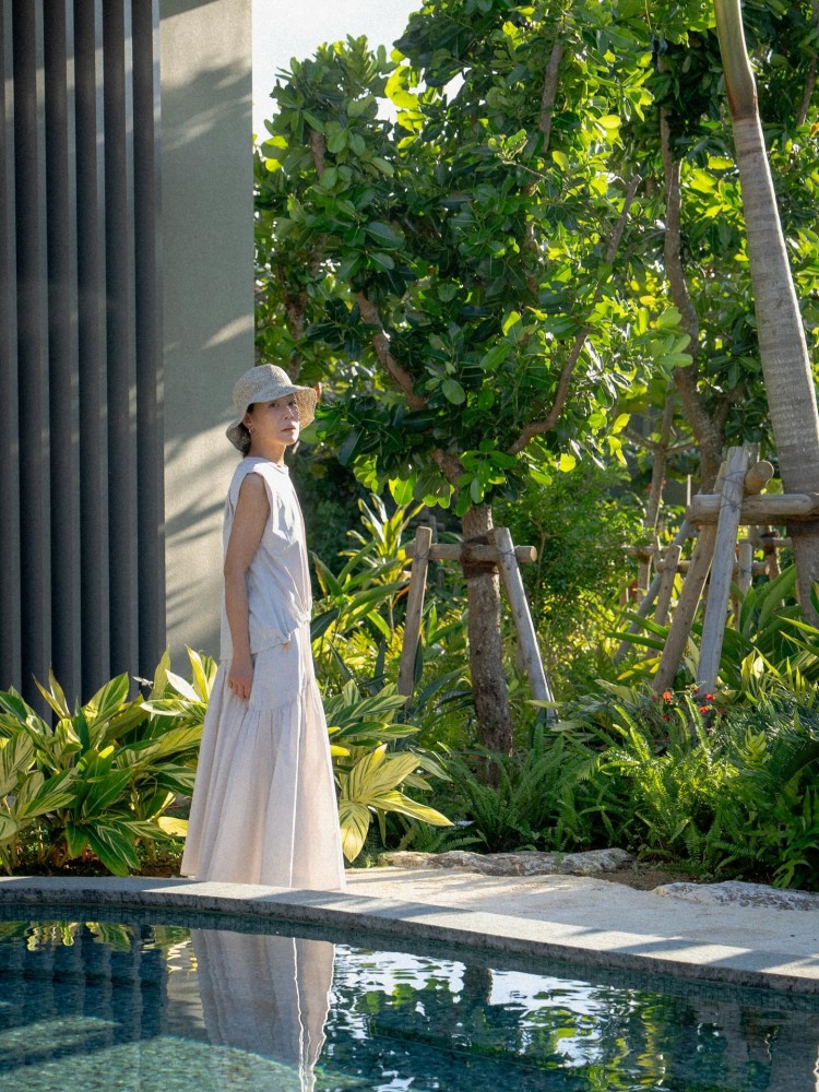 劉若英的度假穿搭選擇了一套米白色及地洋裝，展現毫不費力的優雅，盈垂墜的布料隨步伐自然飄動，寬鬆的剪裁不僅舒適，更自帶隨性、自在的氛圍，搭配一頂編織草帽，米白與大地色系的組合簡直絕配！