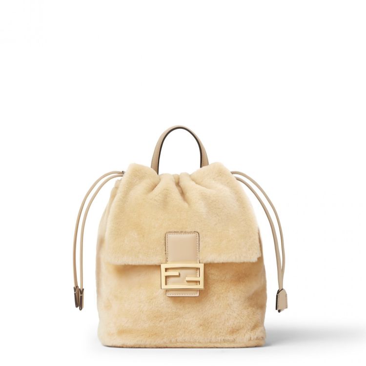 Fendi米色後背包以溫潤的翻羊毛打造，視覺就很有冬日氛圍，中央經典法棍飾扣成為低調亮點，抽繩結合隱藏磁扣的開合設計，使用上順手又安心。