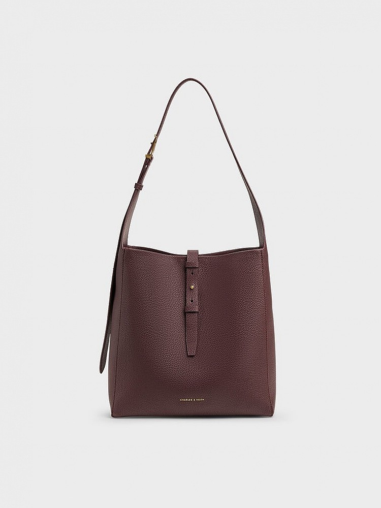 Beryl皮帶釦流浪包以深紅酒莓色調展現沉穩內斂,卻又帶有低調光澤感,包身選用灰褐色荔枝紋PU皮革,觸感細緻、耐磨好打理,搭配皮帶釦與金屬logo吊牌,為簡約輪廓增添精緻質感,是一款兼具氣質與功能性的萬用大包!