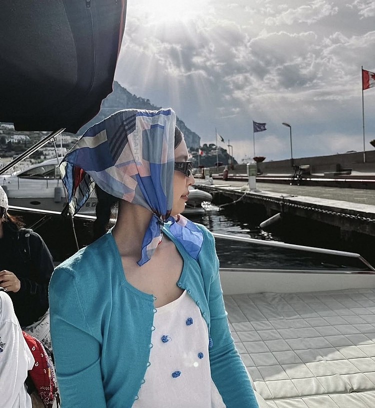 頭巾與服裝在藍白色調中呼應，散發濃厚的度假感，搭配復古墨鏡更添優雅氣質，鞋款選擇透明果凍鞋平衡了整體視覺，浪漫又充滿個性。