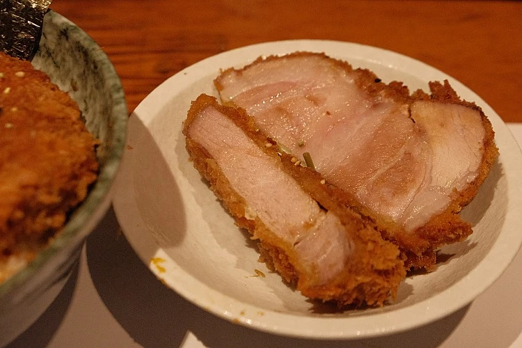 當蛋液與海苔覆蓋在那沉甸甸的豬排上，底下的白飯吸飽了肉汁，口感濕潤卻不軟爛。
