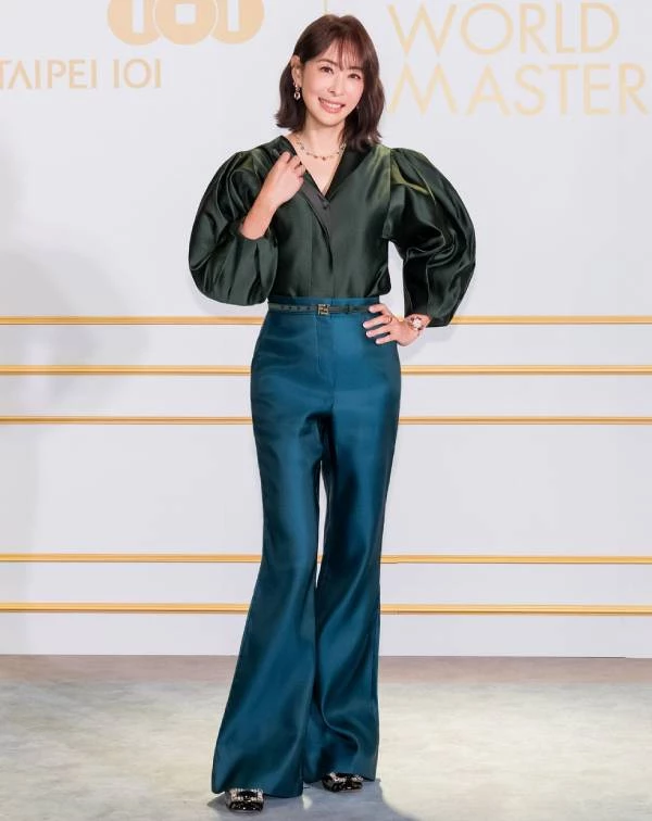 光是賈永婕這套造型,便是精彩演繹了她對於高階撞色的運用所帶來的減齡效果。她大膽選擇沉穩卻自帶光澤感的森林綠澎袖上衣,搭配亮眼的孔雀藍高腰喇叭褲,冷色調之間的撞色組合不僅襯托出白皙膚色,也在視覺上堆疊出細緻的層次美感。