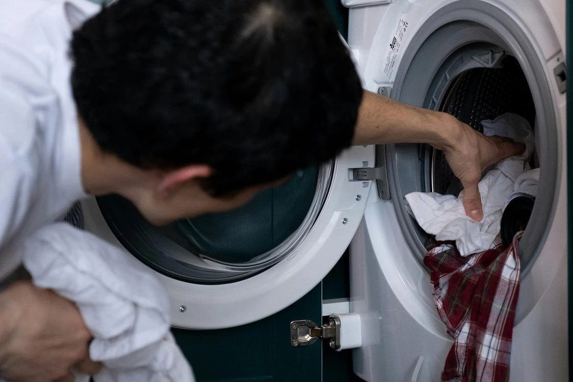 蹲在洗衣機前,正準備將洗好的衣服拿出來
