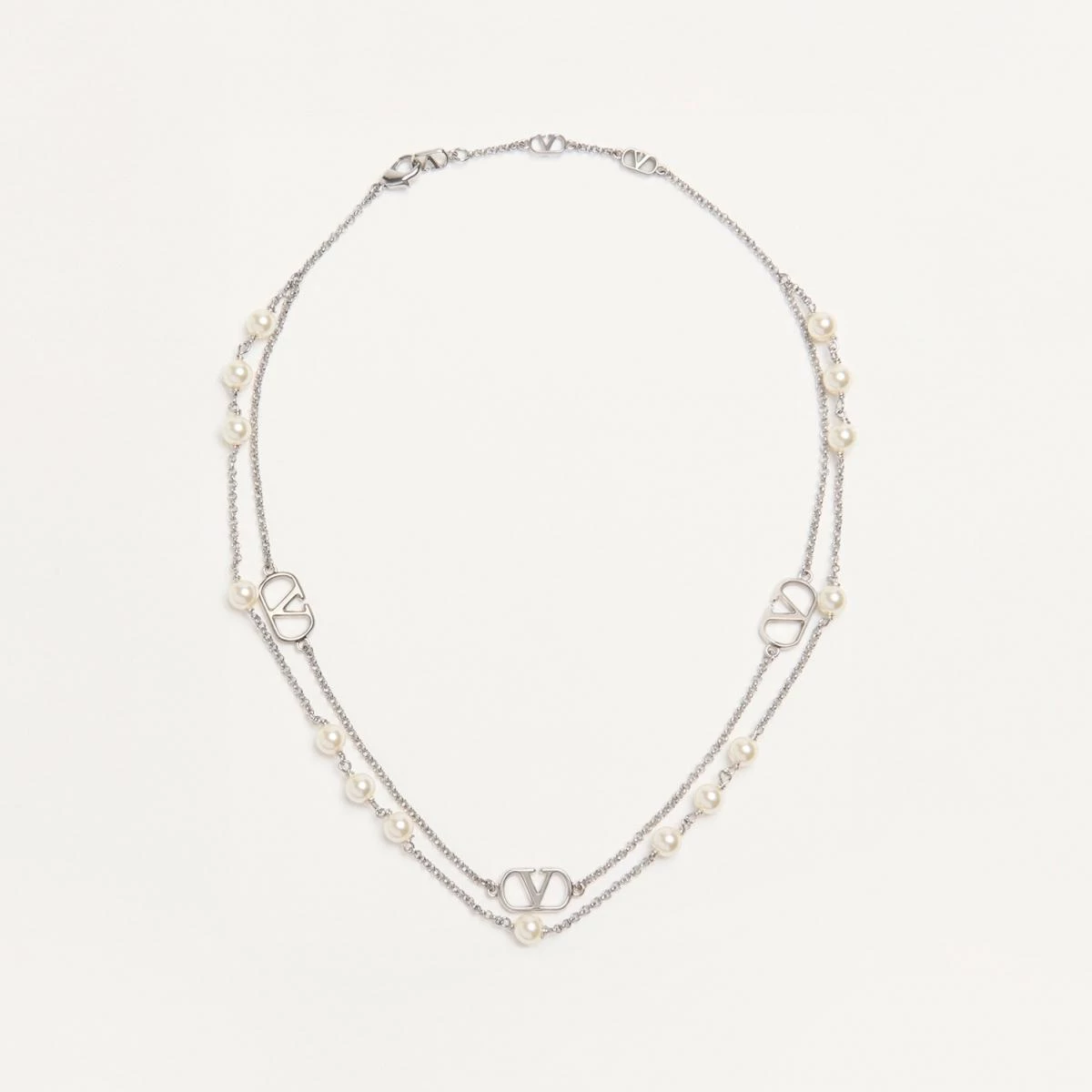 Valentino 的 VLogo Signature 頸鍊以雙鍊設計營造層次美感，一條點綴仿珍珠，一條懸掛經典 VLogo 吊墜，展現義式華麗的細膩浪漫。鍍鈀金屬光澤映襯出柔和珍珠光，彷彿剛柔共存的愛情故事。無論搭配襯衫或洋裝，都能散發不費力的高級感，是職場與約會都能駕馭的萬用款。