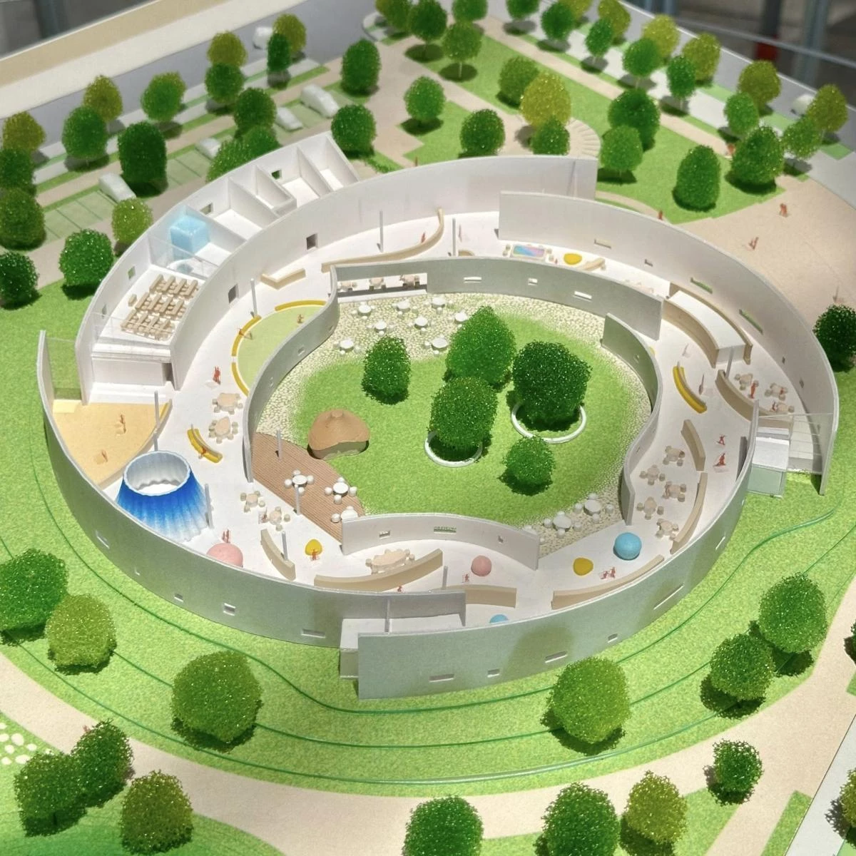 另一個亮點是中庭。建築師嘗試透過量體圍塑出一座內向的綠色庭院。環狀結構所形成的中庭，提供兒童安心遊玩的戶外空間。屋頂與牆面透過綠化設計，結合深簷以有效降低陽光直射，打造節能且舒適的建築。這裡不僅是一座建築物，更是啟發孩童想像力、促進文化活動的空間。