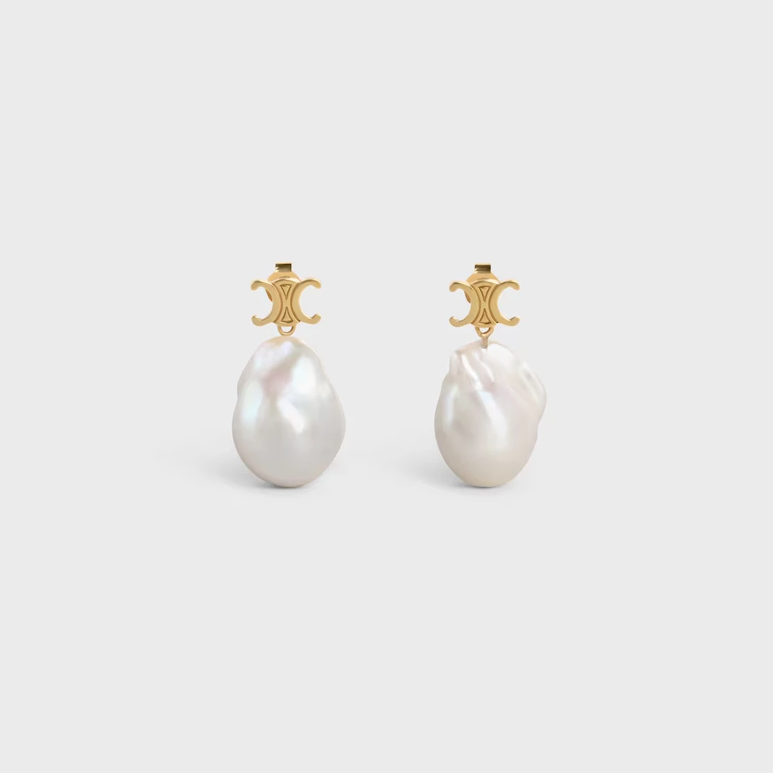 Celine 的珍珠總是有一種冷淡中的性感。這款 Les Perles Baroque 巴洛克風格耳環，以不規則的養殖珍珠搭配金色飾面黃銅，彷彿把大自然的即興語彙直接佩戴於耳間。珍珠本身的天然紋理像被陽光親吻過般熠熠生輝，而上方小巧的凱旋門標誌則為整體添上巴黎式的態度。適合喜歡極簡風格卻又不想「太乖」的人，一秒展現知性又時髦的反差感。