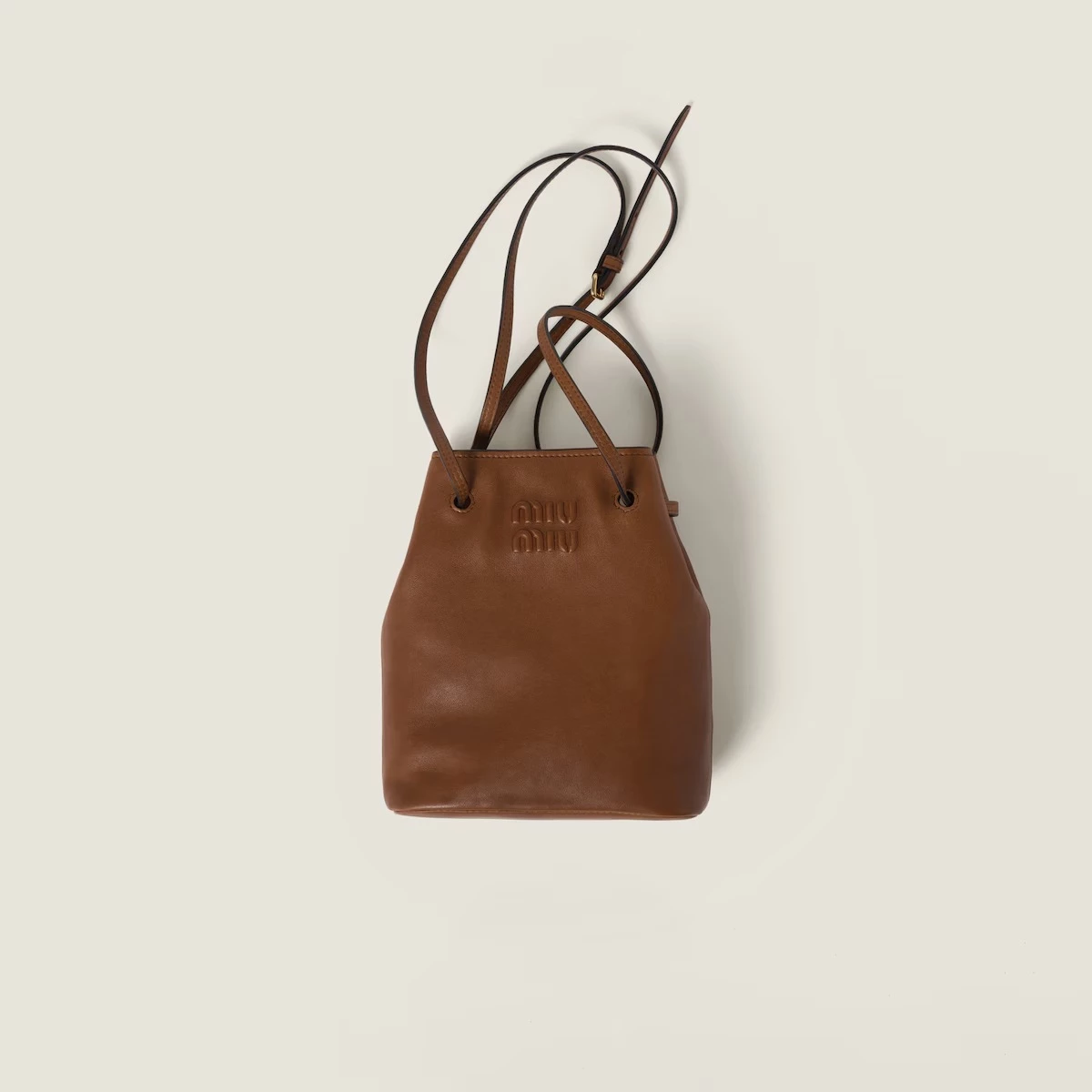 這款焦糖色皮革的 Miu Miu 肩背包，運用品牌代表性的色彩為主軸，並以壓印方式呈現 Logo，讓整體帶有簡約又不失可愛的氣息，此外在面料上則選用精緻柔軟的納帕皮革，更增添其舒適的手感。