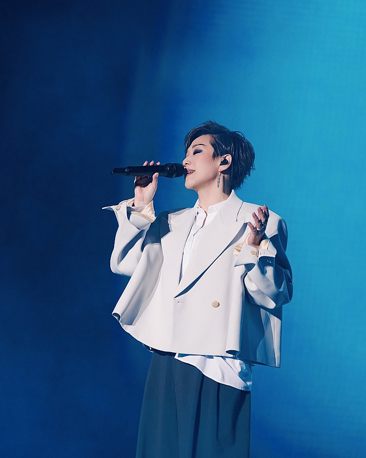 林憶蓮在舞台上選擇以短版西裝外套搭配寬褲的造型，米白色短版西裝外套，透過寬鬆剪裁與金色單扣細節，內搭白襯衫下擺刻意外放，營造出層次感，下身的黑色寬褲拉長身型比例，搭配極簡的線條耳環點綴，整體簡約卻不失舞台張力，將中性率性詮釋得既俐落又高級。