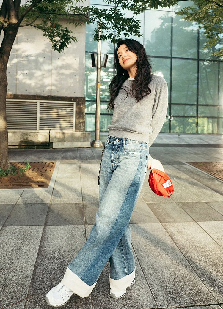 舒淇以麻灰色羊毛針織衫搭配漸層水洗牛仔寬褲，柔軟毛料與寬鬆版型營造慵懶氛圍，為中性色調注入活力與青春感，翻邊褲腳與鬆弛剪裁修飾腿型，也讓整體比例更顯修長。